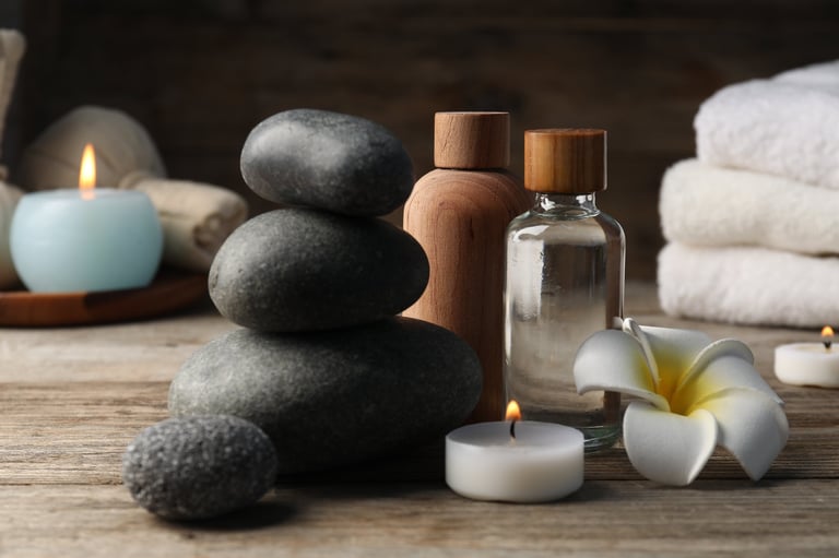 Composition with cosmetic products and spa stones on wooden table, closeup